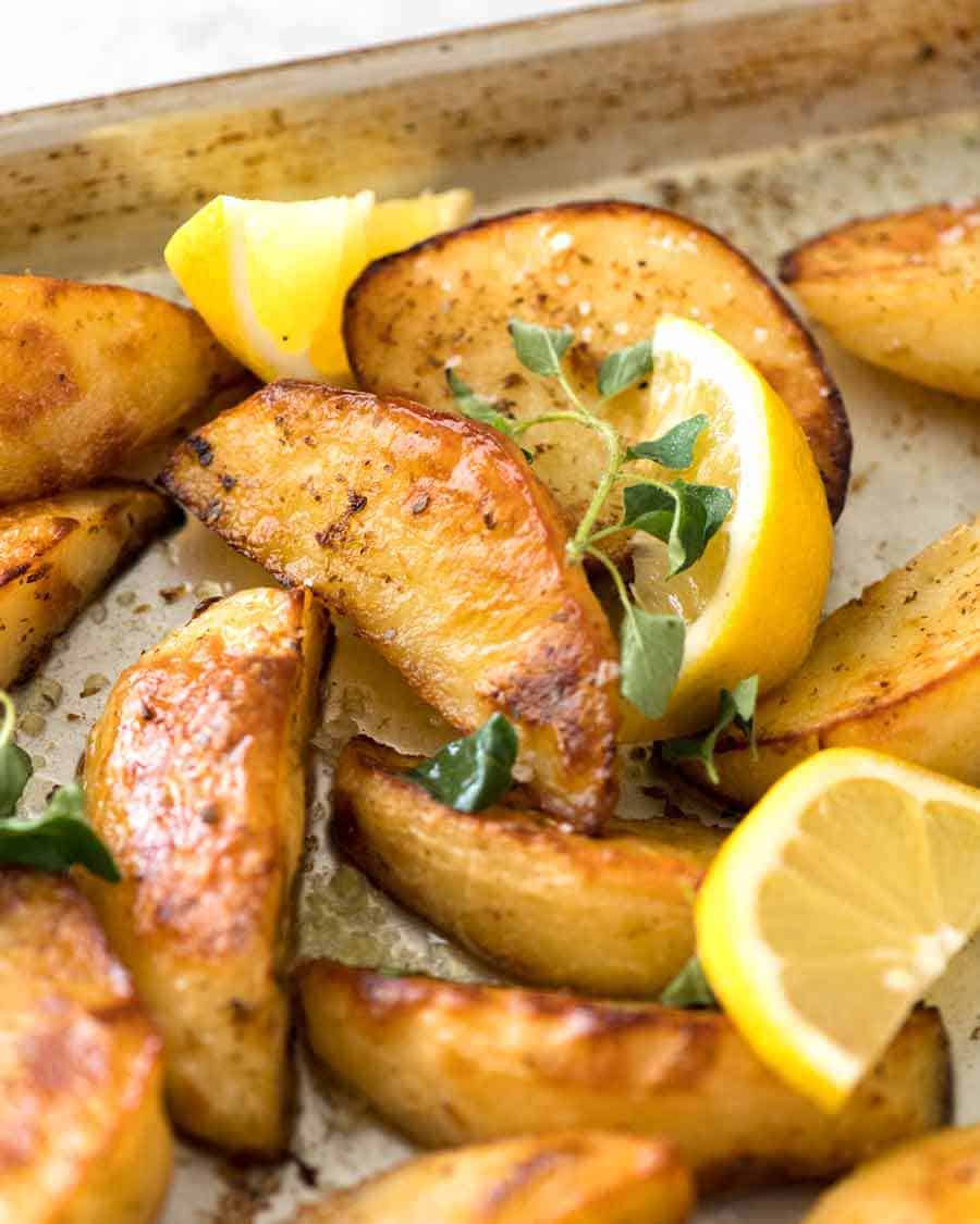 Close up of Greek Lemon Potatoes on a roasting tray, fresh out of the oven