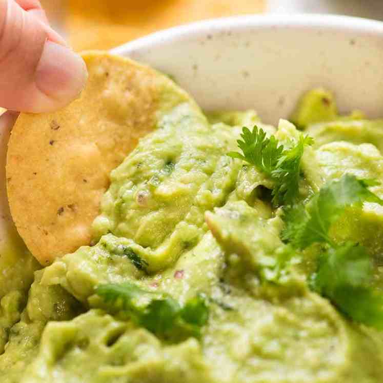 Close up of corn chip being dipped into Guacamole