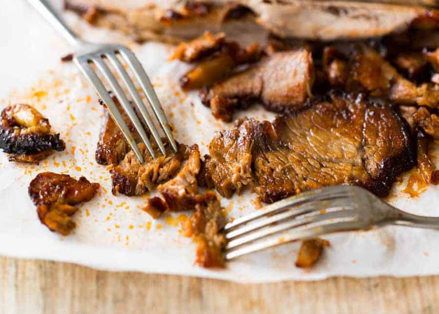 Two forks shredded slices of Slow Cooker Beef Brisket with BBQ Sauce, showing how tender the flesh is.