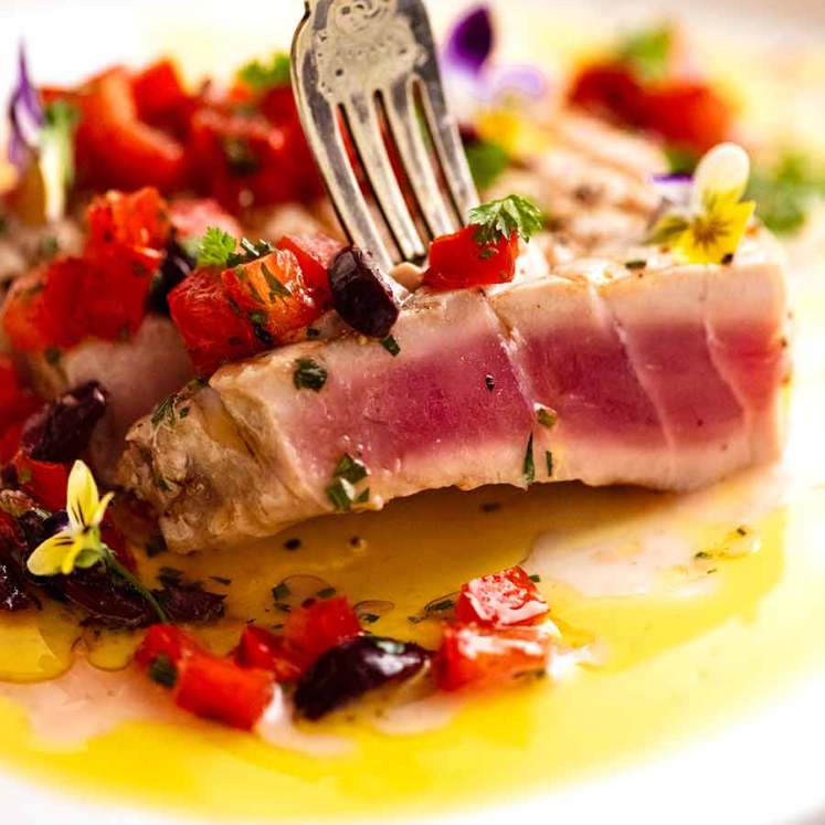 Close up of fork picking up a slice of tuna steak